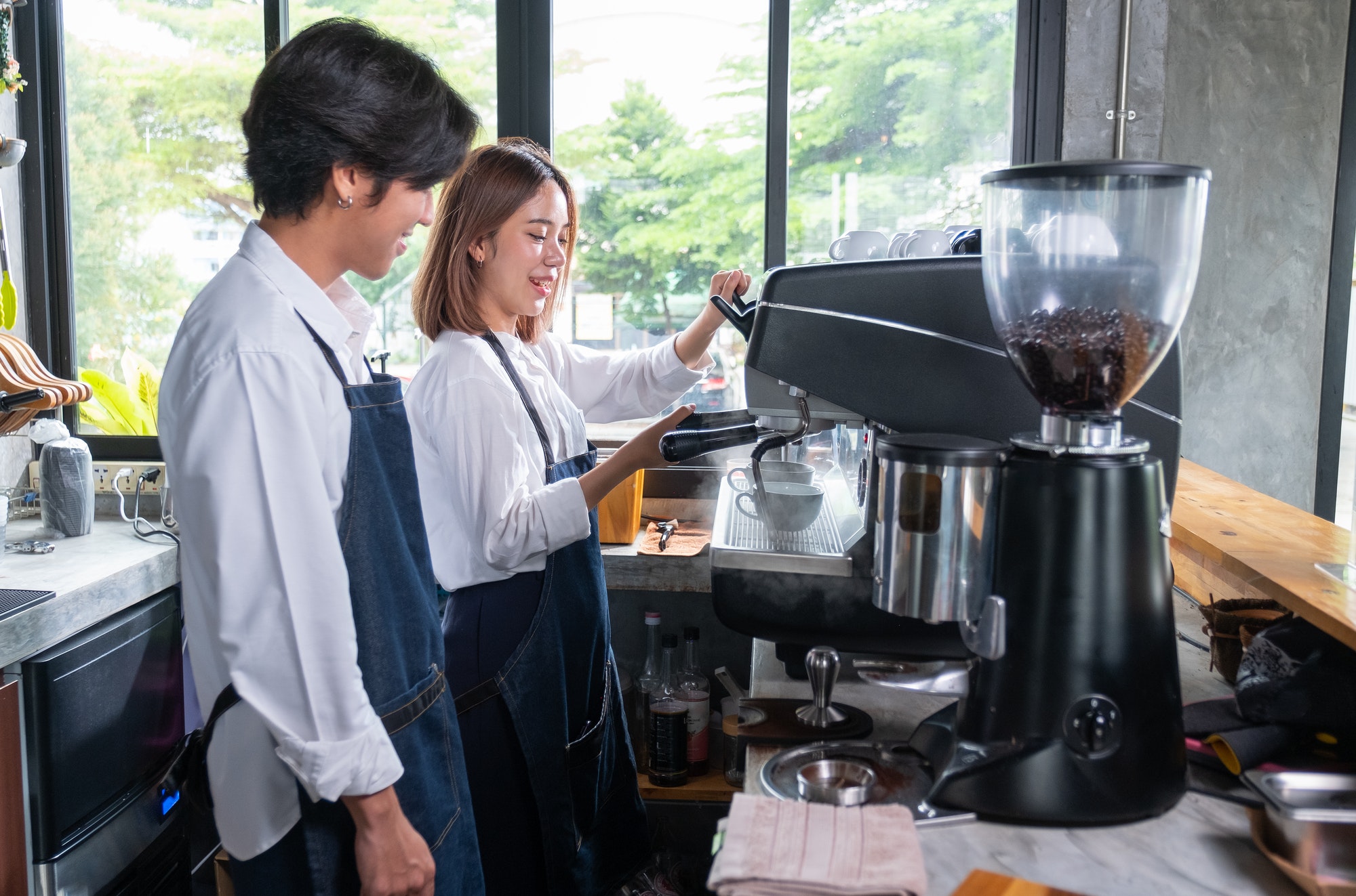 Barista man stand near his co-worker who prepare of produce coffee using coffeemaker