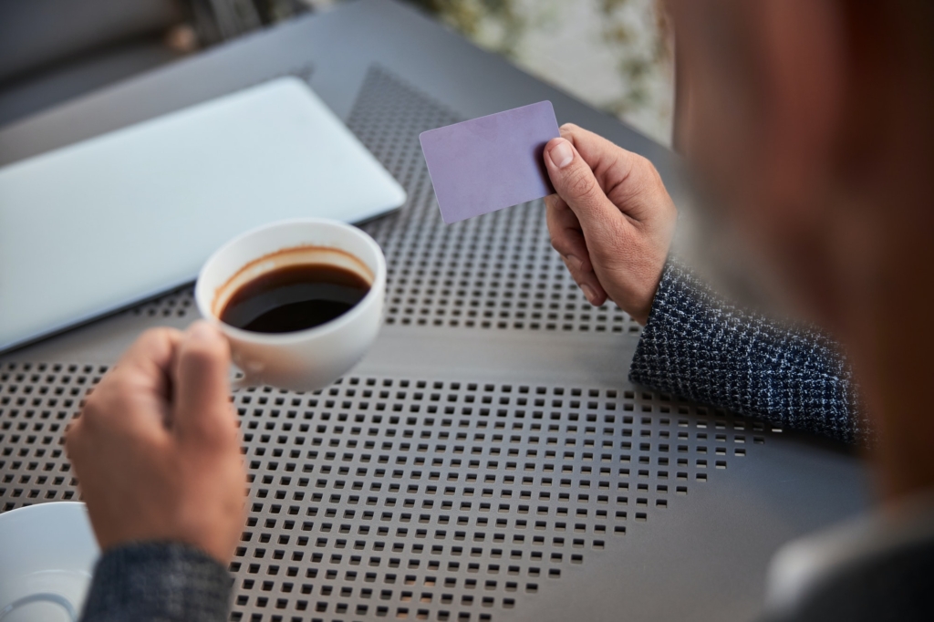 Cup of coffee and a plastic card in man hands