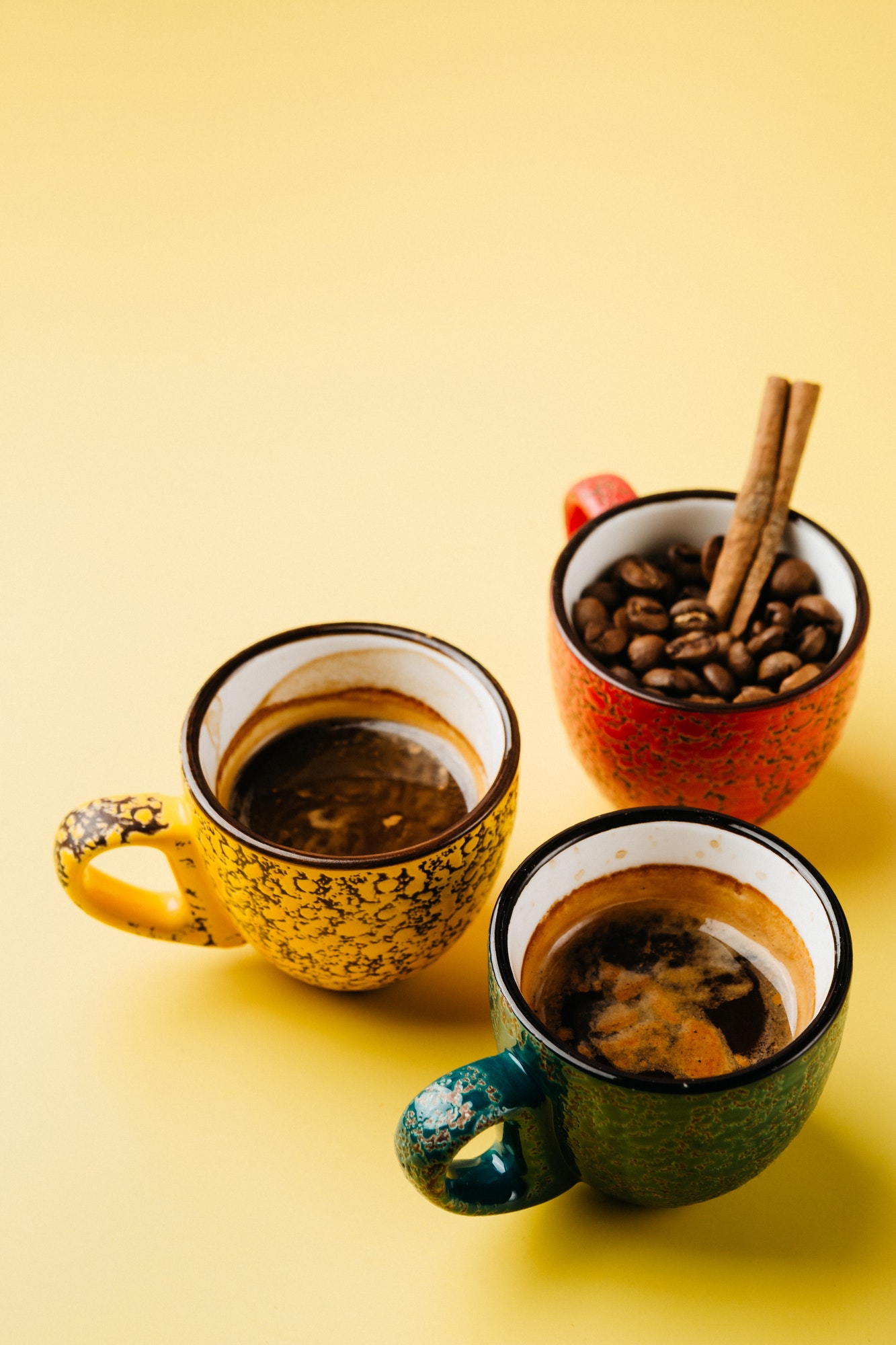 cups with coffee and coffee beans on yellow background