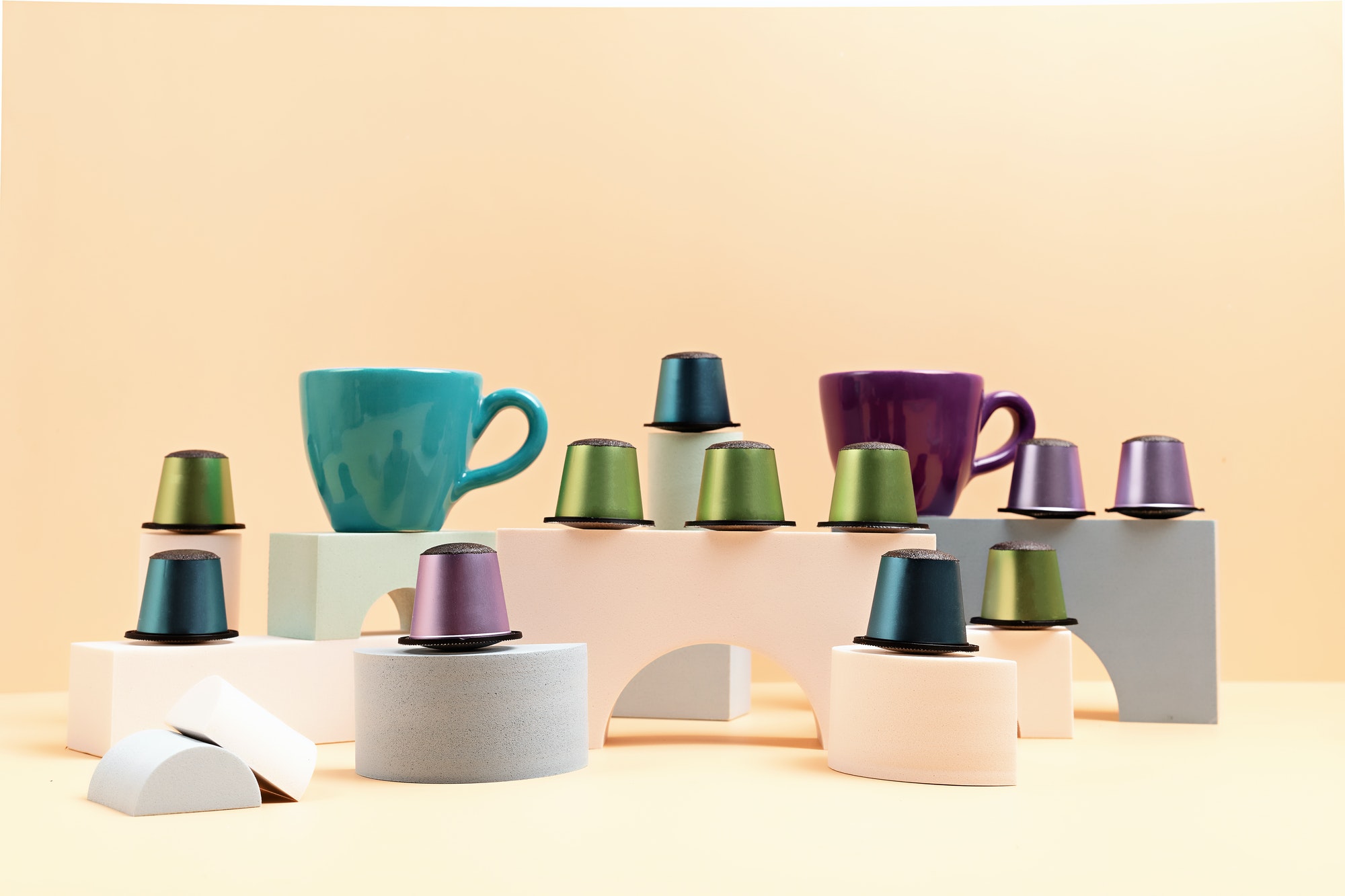 Disposable coffee capsules and cup over green background with copy space on podiums. Morning dose of