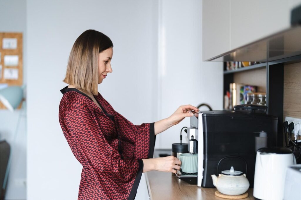 side view of smiling woman looking at microwave in kitchen